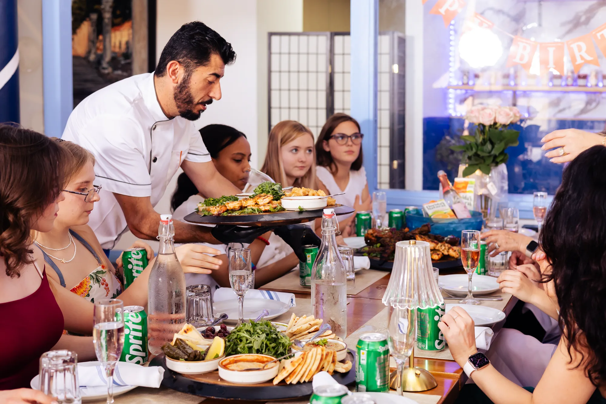 A large group celebrating with a shared feast at Kalimera