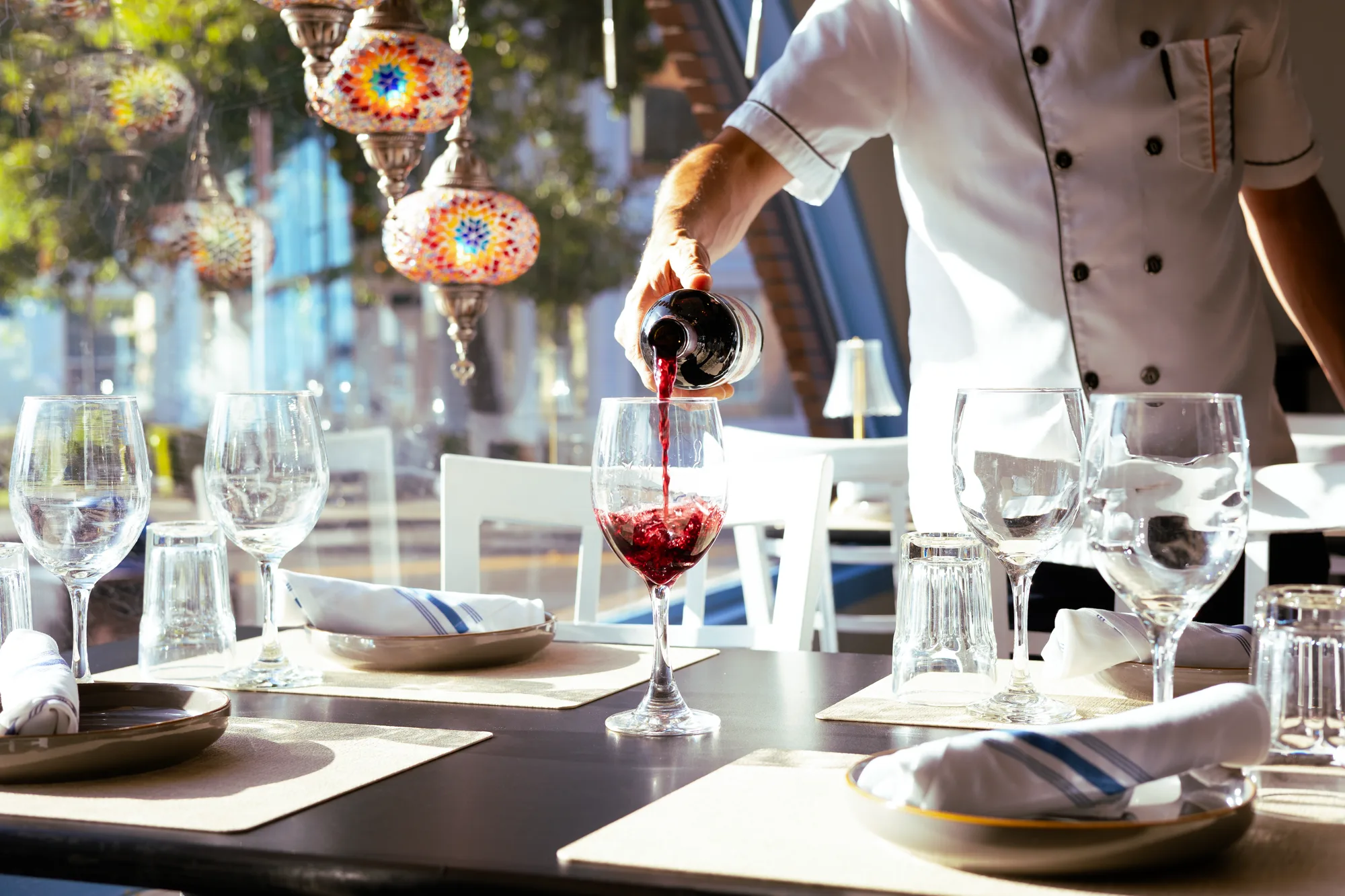 Wine being poured at a table under Turkish mosaic lamps